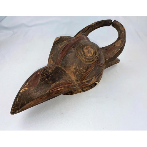 160 - An African tribal mask with hawk like beak and horns, applied paint in carved geometric patterns 43c... 
