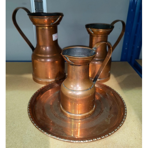 13 - A graduating set of 3 copper jugs in the Arts & Crafts style; a copper circular tray