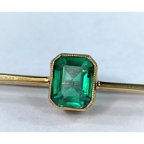 417 - A yellow metal bar brooch stamped 15ct set with a rectangular cushion cut emerald coloured stone 3.5... 