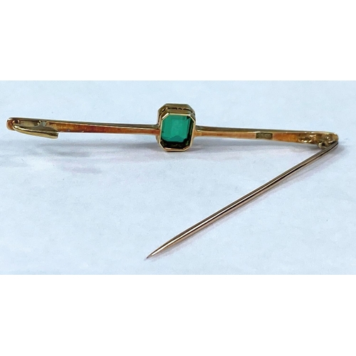 417 - A yellow metal bar brooch stamped 15ct set with a rectangular cushion cut emerald coloured stone 3.5... 