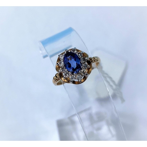 335 - A 9 carat hallmarked gold dress ring set oval sapphire coloured stone, surrounded by clear stones, 2... 