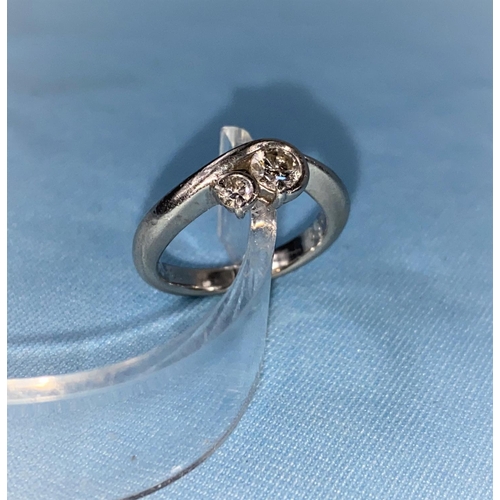 383A - A white metal crossover ring set a large and a small diamond, stamped 'PT900', larger stone approx .... 