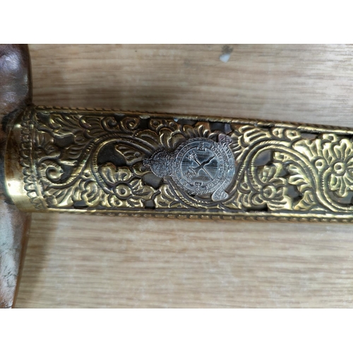 89 - A Malayan presentation Kris, polished wood handle and ornate embossed brass scabbard, with inset sil... 