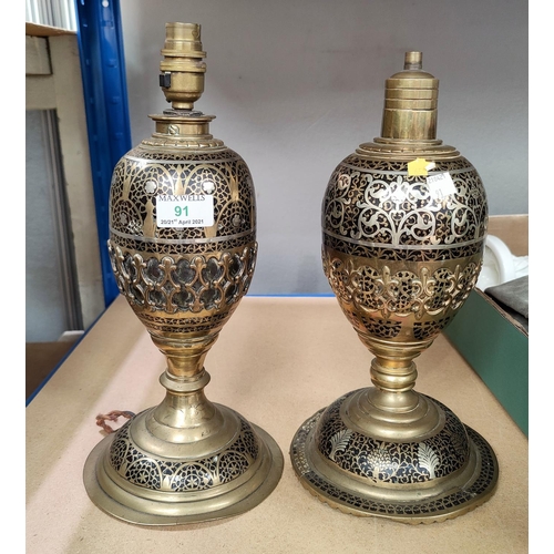 91 - An Islamic pair of brass vases of oval pedestal form, with pierced decoration and silvered metal inl... 