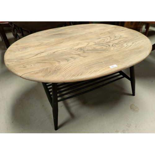 501 - An Ercol oval coffee table with a light wood top and painted legs and under shelf.
