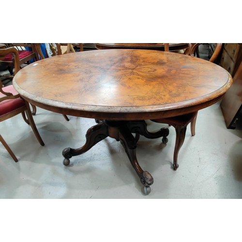 537 - An oval Victorian figured walnut looe table on turned columns triple splay feet