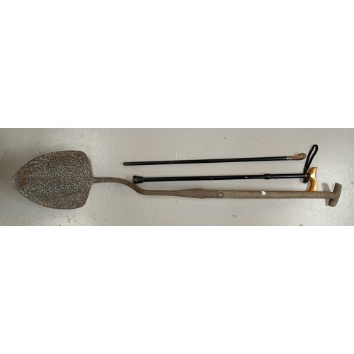 107A - An antique peat shovel/ spade with stepped blade, a horn handled ebonized cane with silver collar an... 