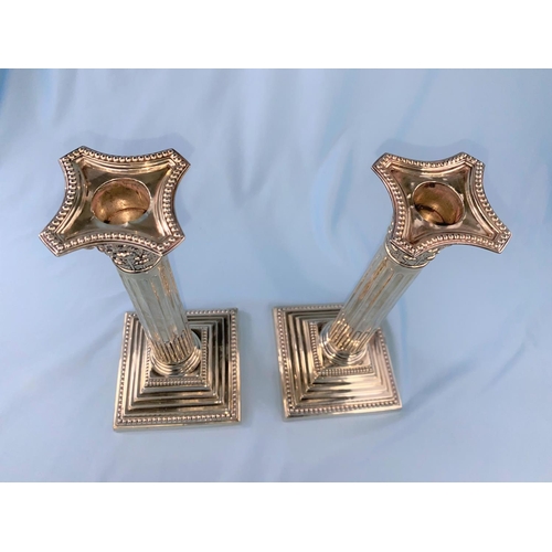 436 - A hallmarked silver pair of candlesticks with Corinthian columns on weighted square stepped bases, L... 