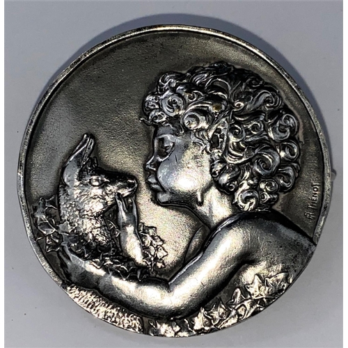 484 - An early 20th century white metal circular brooch by Francois Thenot, cast with boy and lamb surroun... 