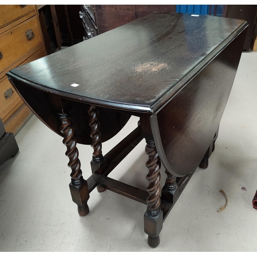 567 - A 1930's oak dining table with oval dropleaf top on barley twist legs