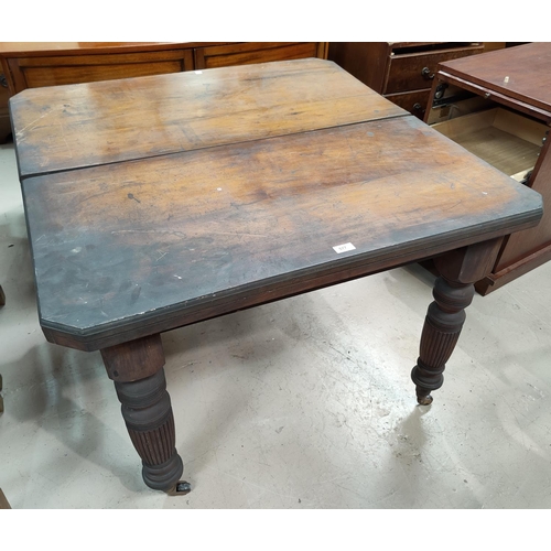 577 - An Edwardian walnut wind out dining table with canted rectangular top, on turned reeded legs and cas... 