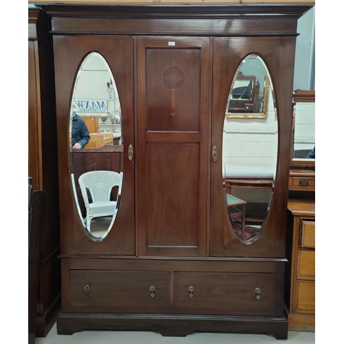 613 - An Edwardian inlaid mahogany double wardrobe in the Sheraton style, with twin oval mirror doors and ... 