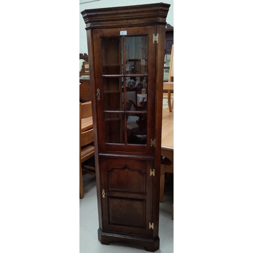 631 - A reproduction distressed oak corner cupboard, full height with glazed door over ogee panelled door,... 