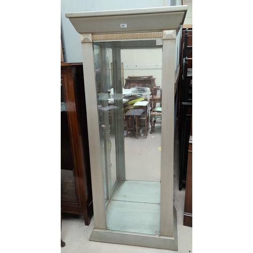 648 - A tall narrow display cabinet enclosed by single door in silvered finish