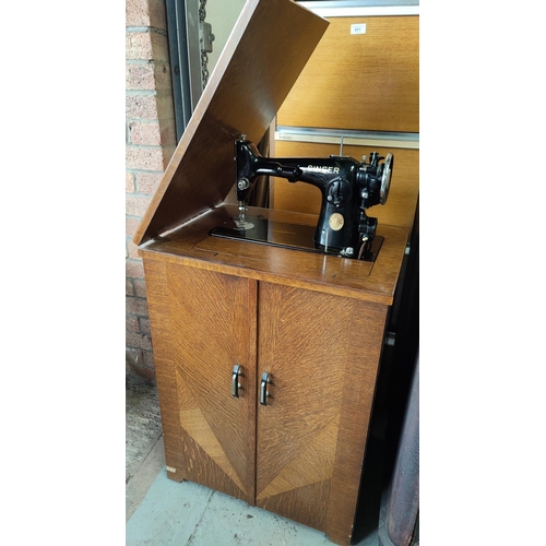 672 - A 1930's Singer treadle sewing machine in veneered oak cabinet