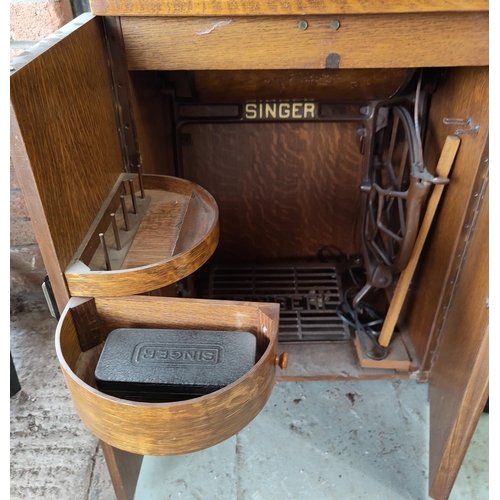 672 - A 1930's Singer treadle sewing machine in veneered oak cabinet