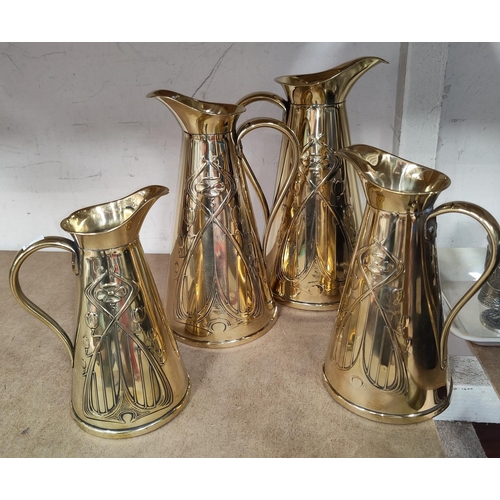 82 - A graduating set of 4 tapering brass jugs with Art Nouveau decoration