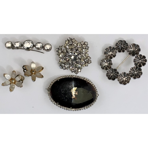 485 - A circular silver floral brooch, a faceted clear stone brooch, two others and a pair of clip-on earr... 