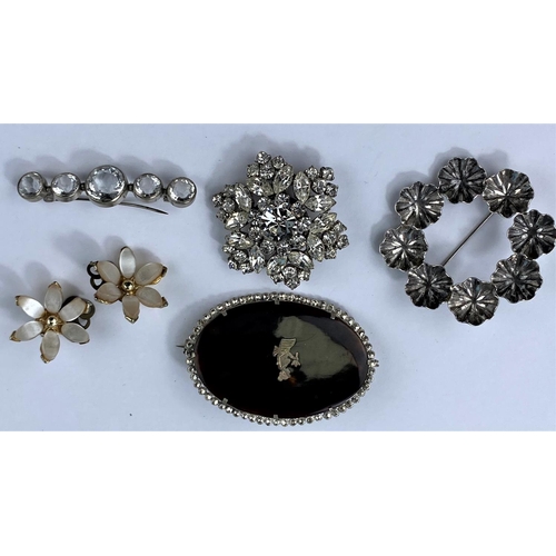 485 - A circular silver floral brooch, a faceted clear stone brooch, two others and a pair of clip-on earr... 