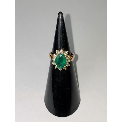 418 - An 18ct gold dress ring set with a large faceted oval emerald, 11mm x 7mm and surrounded by 12 diamo... 