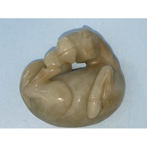 336 - A Chinese jade coloured hardstone carving of a foal curled up on associated intricately carved woode... 