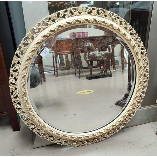 557 - A circular mirror, with pierced cream frame, diameter 63cm.