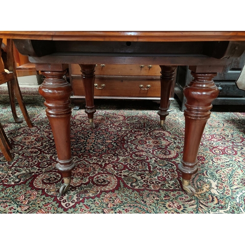 640 - A Victorian dining table with extending oval top and spare leaf, on turned legs and castors, extende... 