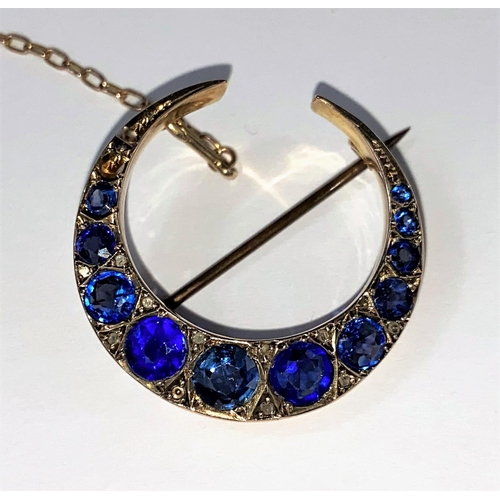 512 - An early 20th century 9ct gold crescent brooch sapphire and other stones (replacements) interspersed... 