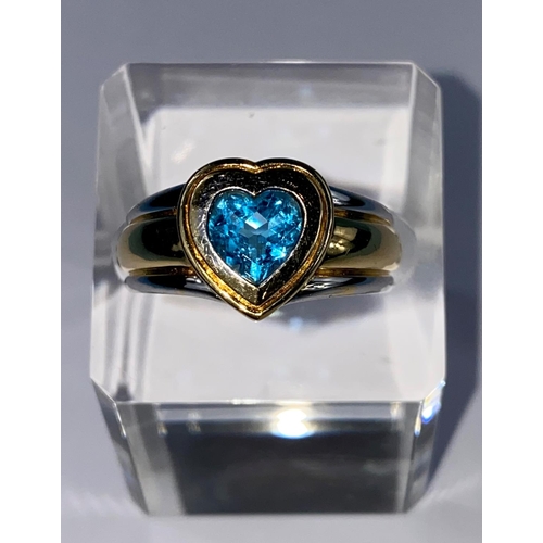 534 - A lady's 18ct hallmarked two tone gold dress ring on a broad shank and blue stone in heart setting, ... 
