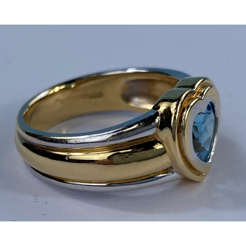 534 - A lady's 18ct hallmarked two tone gold dress ring on a broad shank and blue stone in heart setting, ... 