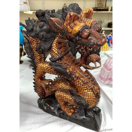 437A - A South East Asian wooden carved figure of a three clawed dragon height 38cm