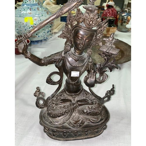 466A - A Tibetan bronze figure of seated buddha with raised sword in one hand, seated in prayer position he... 
