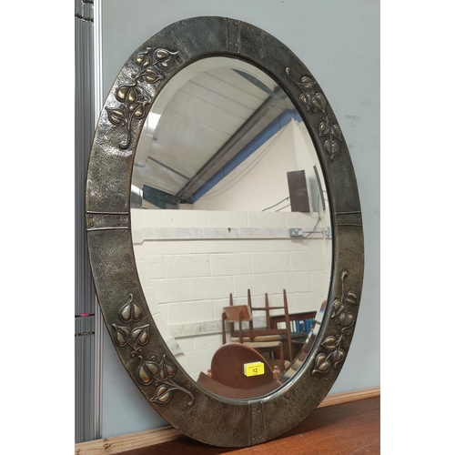 12 - An oval wall mirror in Art Nouveau anodised embossed frame (In good condition with a couple of crimp... 