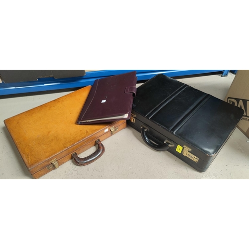 47 - A brown and a black leather brief cases; a leather writing case