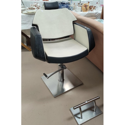 667 - A vintage barber's chair in black and cream leather effect on swivel rise and fall frame and brushed... 