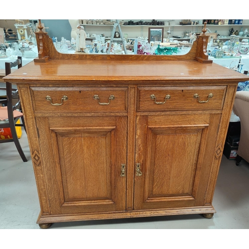 668 - A large Golden Oak sideboard/side cabinet with doubled paneled doors, two drawers with brass drop ha... 