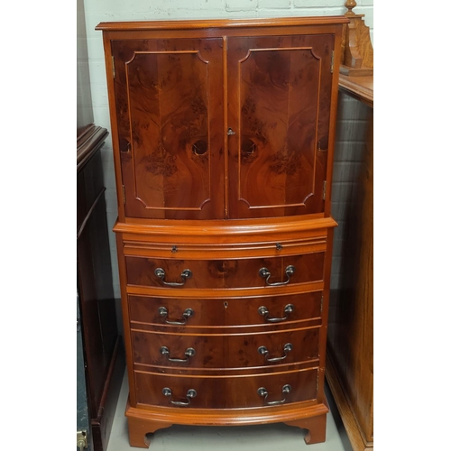 690 - A reproduction Yew wood drinks cabinet in the form of cupboard on chest with double cupboard and 4 d... 