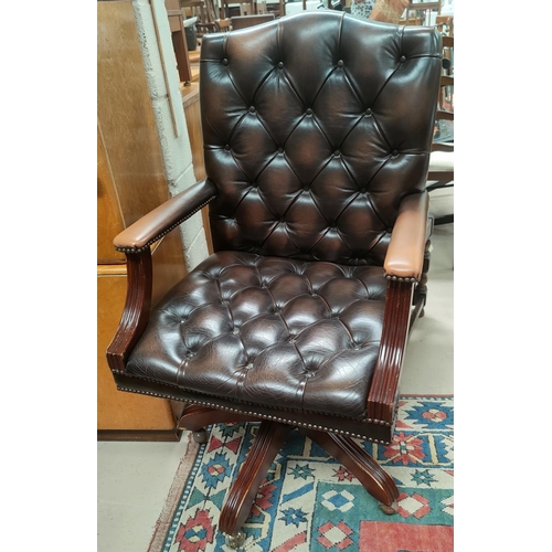 696 - An office swivel armchair with deep button back leather effect upholstery and studded edging