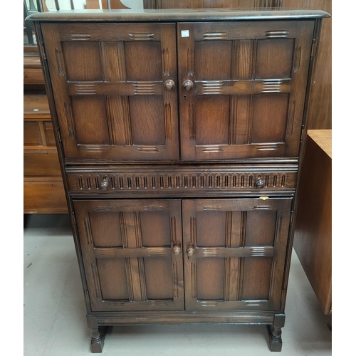 704 - An Ercol traditional style cocktail cabinet, fitted cupboards and central drawer, 82 cm