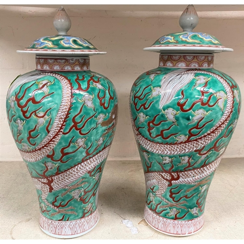 445 - A pair of Chinese green ground lidded baluster vases with dragon decoration lids bearing marks, heig... 