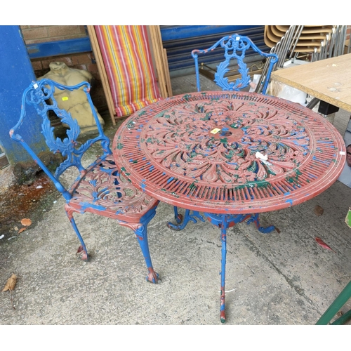 658 - A Victorian style cast metal circular garden table and two chairs (one table leg broken needs weldin... 
