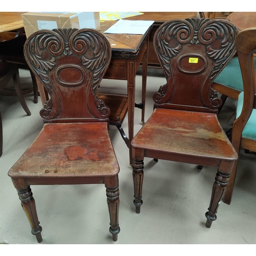 677 - A pair of mahogany hall chairs with carved backs, solid seats and tapering carved legs
