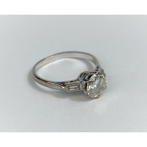 523 - A diamond set ring with central bright cut stone and small baguette cut stone to either shoulder, on... 