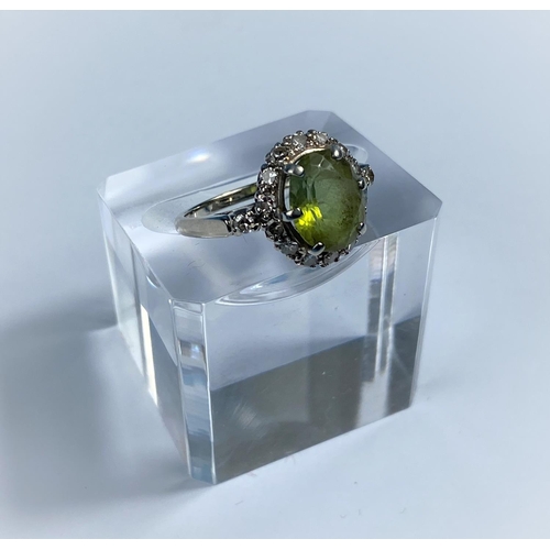 568 - A yellow metal dress ring set central peridot surrounded by 14 diamonds, stamped '14K', 3.9 gm