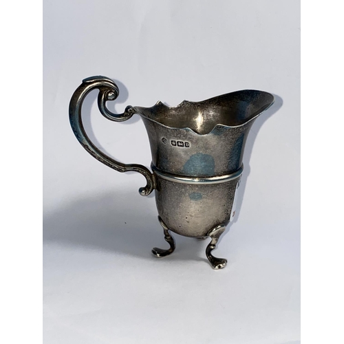 570 - A hallmarked silver cream jug, helmet shaped on triple feet, Sheffield 1926, 2.7 oz