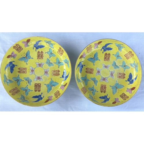 346E - A pair of Chinese yellow ground dishes decorated in polychrome with butterflies to the interior and ... 