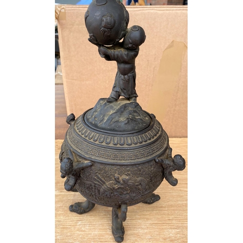 353b - A Japanese bronze lidded pot on three dragon head feet, the lid with child holding large ball, chara... 
