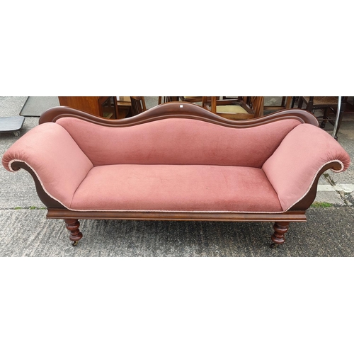 822 - A Victorian double scroll end mahogany settee on turned legs and castors in pink dralon