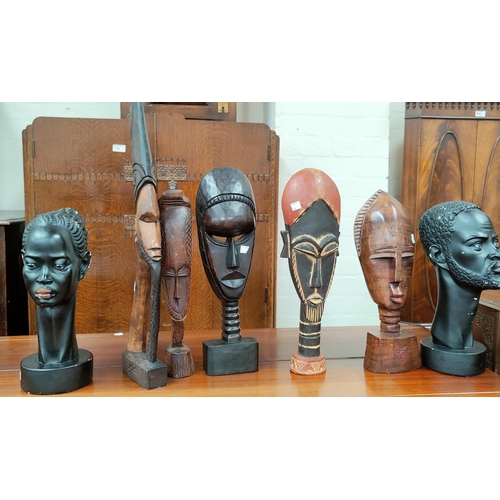 104 - A pair of African male and female head in ebonised cast plaster; 4 African freestanding tribal masks