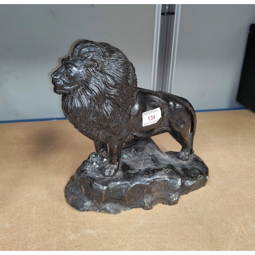 134 - A painted bronze depicting a lion on a rock length 36cm